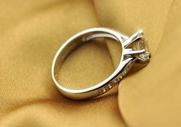 My Store solitaire engagement ring in polished white gold with a six-prong setting and pavé accents on a gold fabric