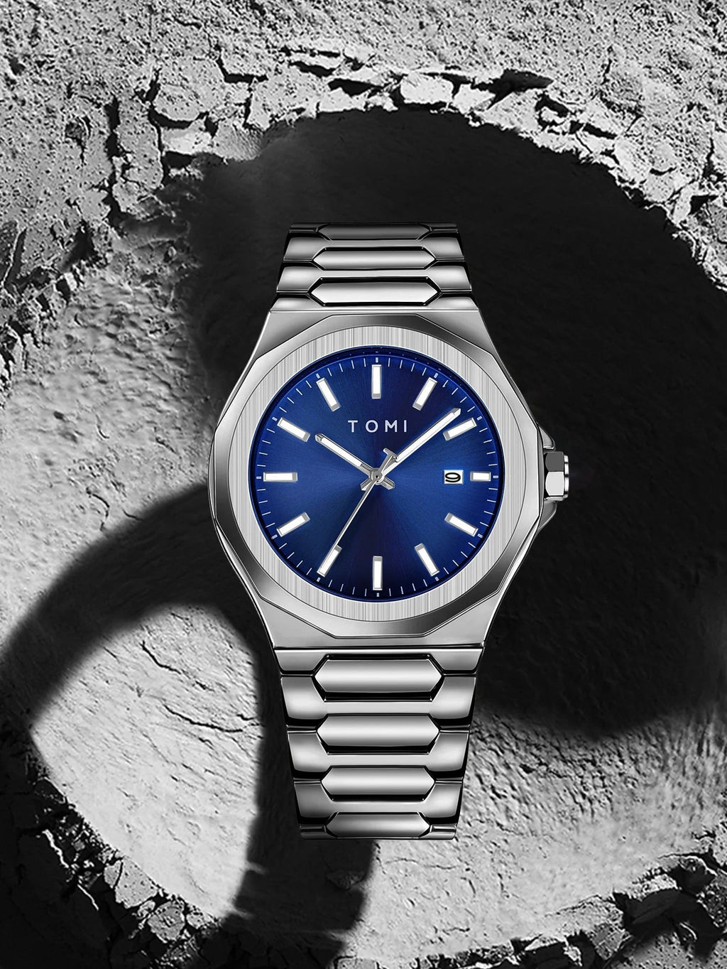 My Store TOMI luxury stainless steel wristwatch with a blue sunray dial and integrated bracelet on a crater background
